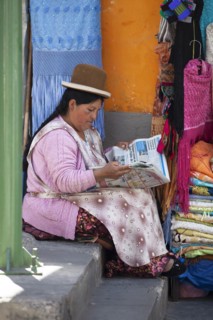 Bolivian woman wearing a traditional hat reading a newspaper