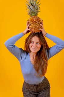 Woman with a pineapple in sunglasses in a studio on a yellow background