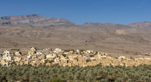 Abandoned ghost town of Al Hamra with Hajar Mountains in the background