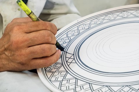 Craftsman painting and decorating ceramic products in pottery factory in Fez
