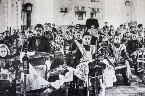 Old archival picture of school children posing in lacemaking class in early twentieth Flanders