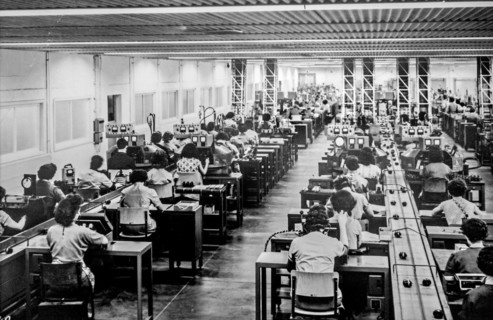 Old black and white archival photograph showing female workers manufacturing small electric motors in factory in the 1950s