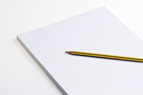 Blank pad of white paper with a pencil on a white background