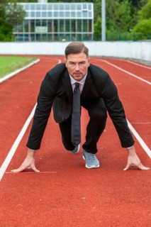 Man in a suit on a running track in starting position