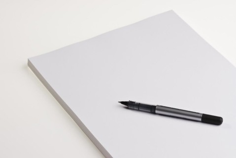 Blank pad of white paper with a pen on a white background