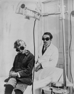 1930 photograph showing doctor and child patient with goggles during light therapy