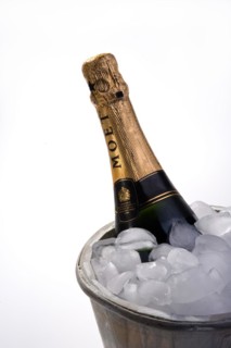 Bottle of champagne in ice bucket full of ice and two empty champagne flutes
