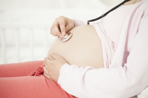 Pregnant woman with stethoscope on baby belly | MR:yes NH_pregnant_belly_mr