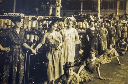 Old archival photograph showing female workers posing in spinning mill in the early twentieth century