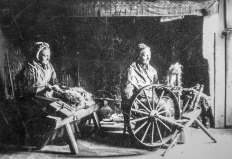 Early 20th century photograph showing two old female home spinners using wooden spinning wheel and hackle