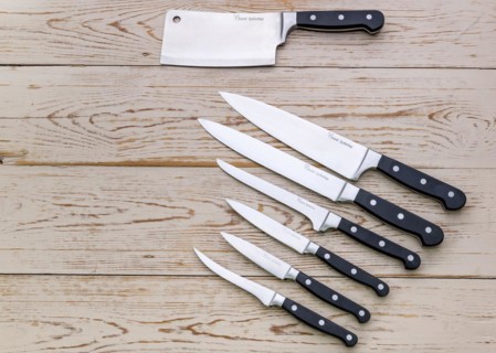 An assortment of various kitchen knives on a wooden background