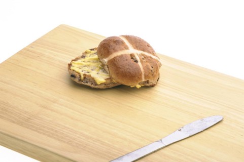 Hot cross bun with knife on a wooden board