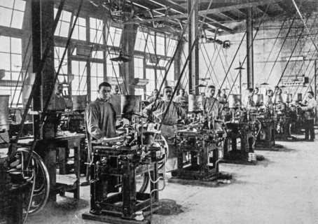 Early 20th century black and white archival photo showing workers and machines for casting types for typesetters at foundry floor of type foundry
