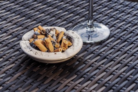 Ashtray full with cigarette ends on a rattan table