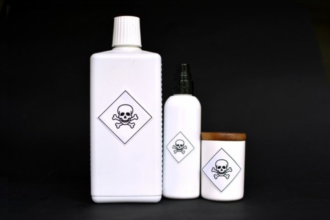 Different shaped white containers with poison labels on black background