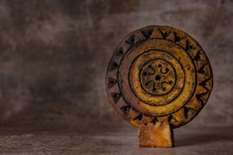 Close-up of a hand-carved and hand-painted stone disc