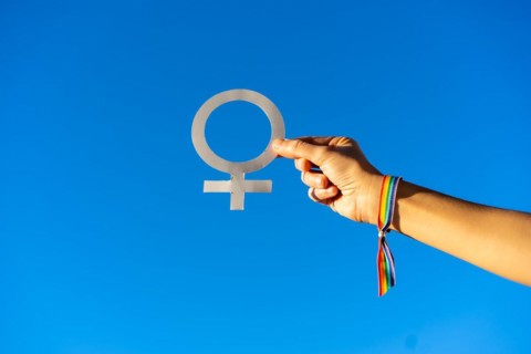 Blue sky background with a hand of a woman with female symbol in favor of feminism