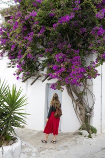Young woman with red skirt in the alleys of the old town Chora