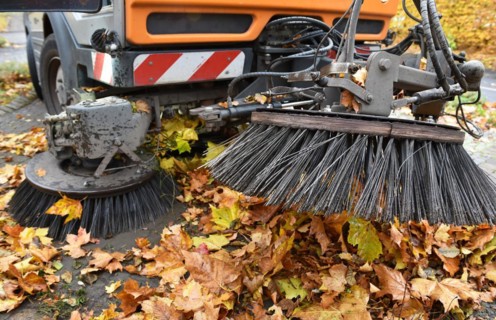 Sweeper sweeps wilted leaves from the road