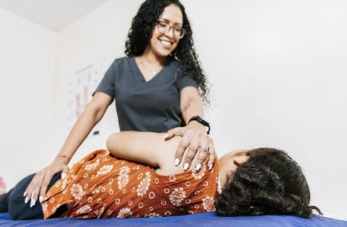 Physiotherapist rehabilitating shoulder to patient lying on her side