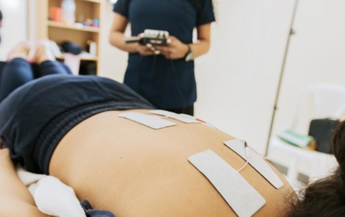 Physiotherapist electrostimulating a patient