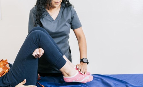 Professional physiotherapist assisting patient in leg rehabilitation
