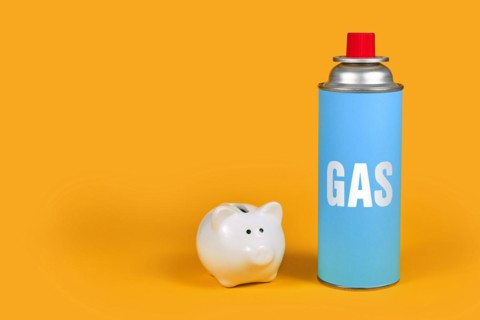 Gas cartridge bottle with piggy bank on yellow background