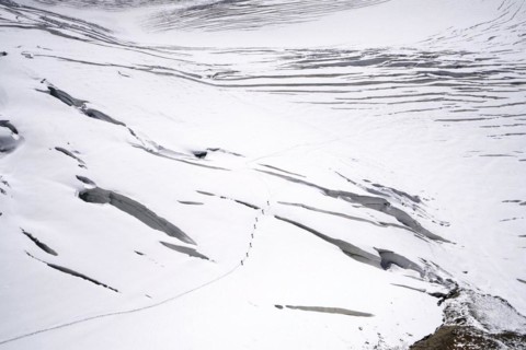 Alpine glacier hikers hike through the snow and ice