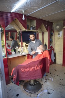 Barber shaves a customer in his shop