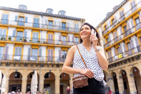 A woman in a hat visiting the city and talking on the phone