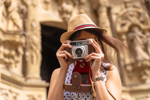 Pretty tourist in hat visiting church with photo camera