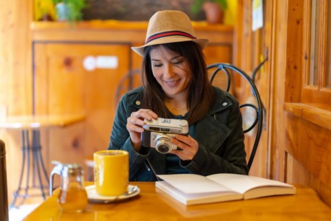 A tourist girl with a photo camera having a tea in a cafeteria terrace