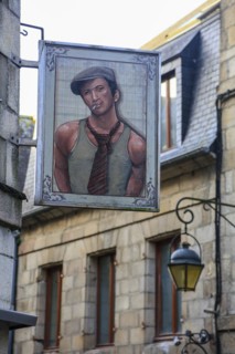 Sign of a clothing shop with portrait of young man in vest with tie