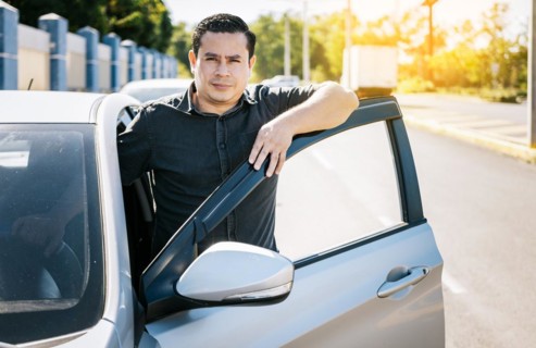 Close up of driver leaning on the car door in the street