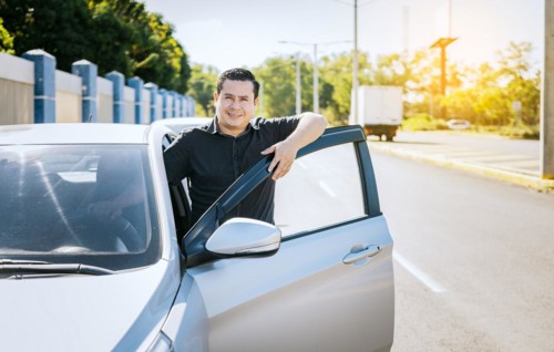 Smiling driver leaning on the car door