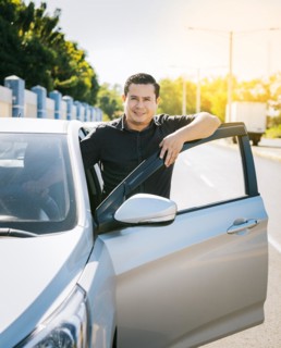 Happy driver leaning on the car door in the street