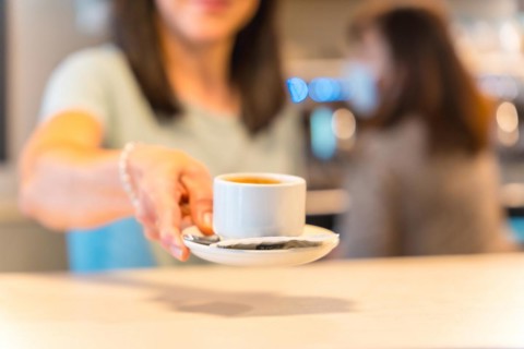 Hands of female coffee shop owner with a latte in her hand