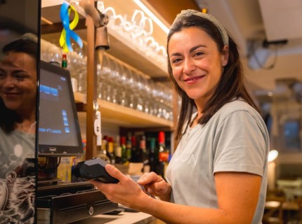 Brunette caucasian waitress cashing with card in coffee shop