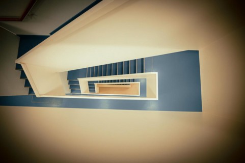 Staircase with white banister and blue vinyl floor from top to bottom