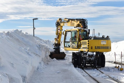 Two-way excavator clears the tracks of the Harz narrow-gauge railway from snow on the Brocken