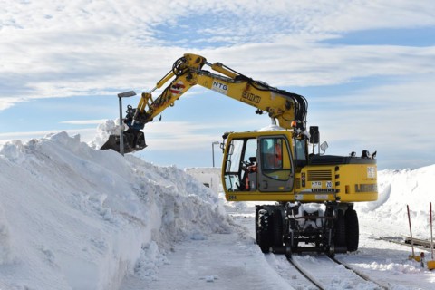 Two-way excavator clears the tracks of the Harz narrow-gauge railway from snow on the Brocken