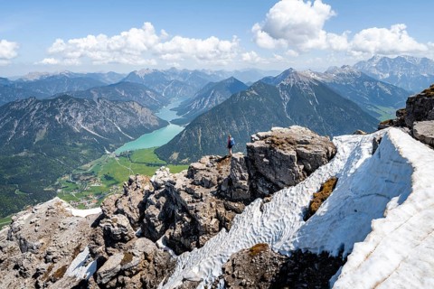 Hiker looking down from Thaneller to Plansee and eastern Lechtal Alps