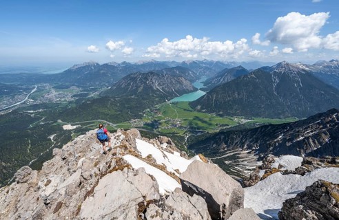 Hiker looking down from Thaneller to Plansee and eastern Lechtal Alps