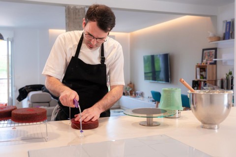 A man baker bakes a red velvet cake at home