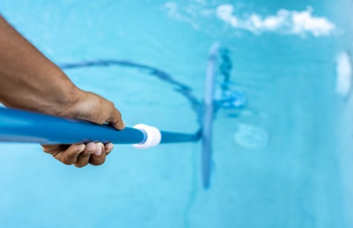 People cleaning swimming pool with suction hose