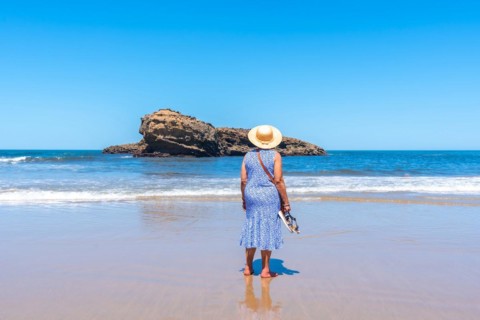 An elderly woman on vacation looking at the sea on the beach in Biarritz