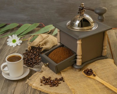 Coffee beans and ground coffee with coffee grinder and flowers