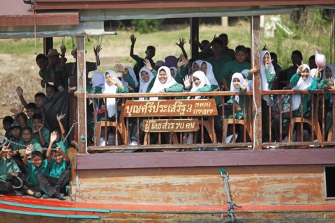 Schoolgirl in school uniform on a rice barge on the Chao Phraya