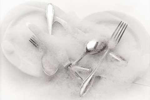 Freshly washed crockery and cutlery in soapy water