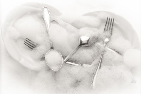 Freshly washed crockery and cutlery in soapy water
